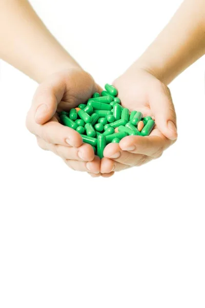 Manos está dando cápsulas verdes y pastillas de color naranja sobre fondo blanco . —  Fotos de Stock