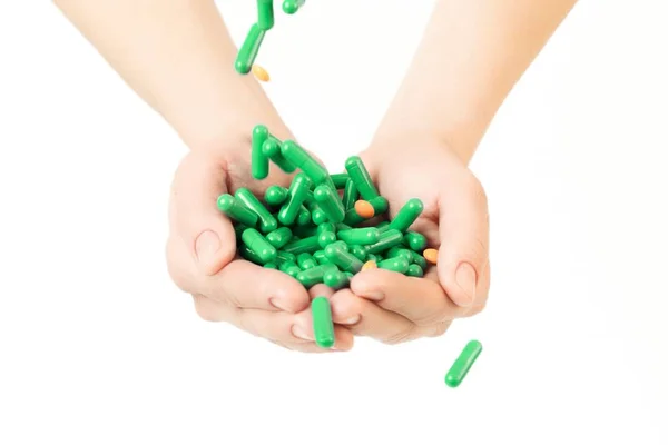 Manos está dando cápsulas verdes y pastillas de color naranja sobre fondo blanco . —  Fotos de Stock