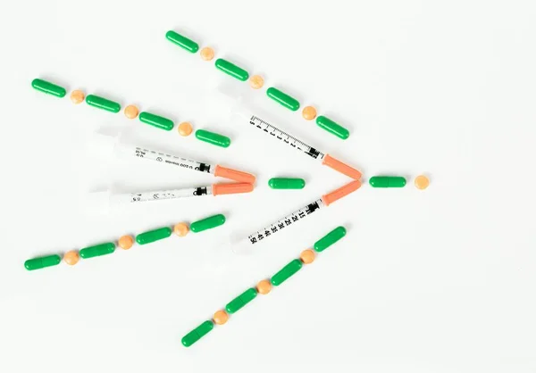 Шприц с инсулином, таблетки и капсулы в форме правой стрелки — стоковое фото