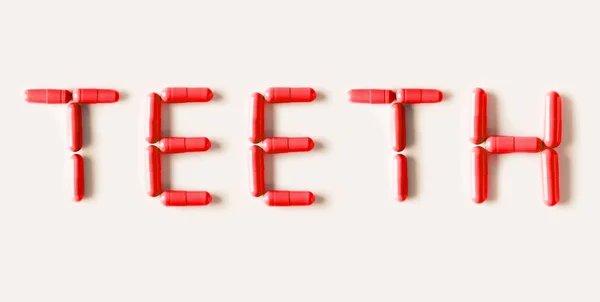 Prášky na červené kapsle ve tvaru slova zuby. Splácení, samostatný. — Stock fotografie