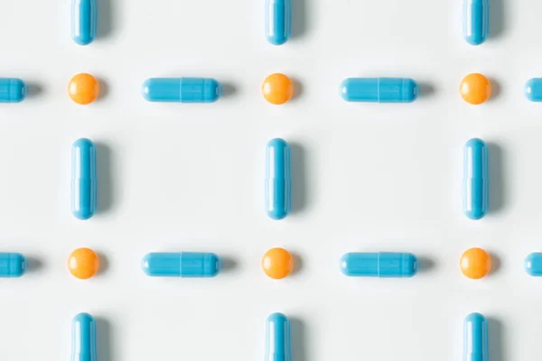 Pilules médicales bleues et modèle de capsules sur fond blanc. plan plat, vue sur le dessus . — Photo