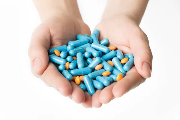 Руки дають сині капсули і апельсинові таблетки на білому тлі . — стокове фото