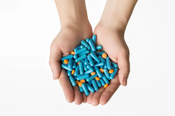Τα χέρια δίνοντας πορτοκαλί χάπια και κάψουλες μπλε σε άσπρο φόντο. — Φωτογραφία Αρχείου