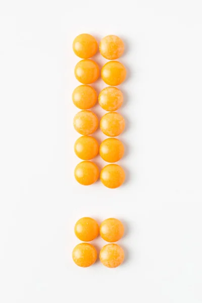 Exclamation made of yellow pills on white background — Stock Photo, Image