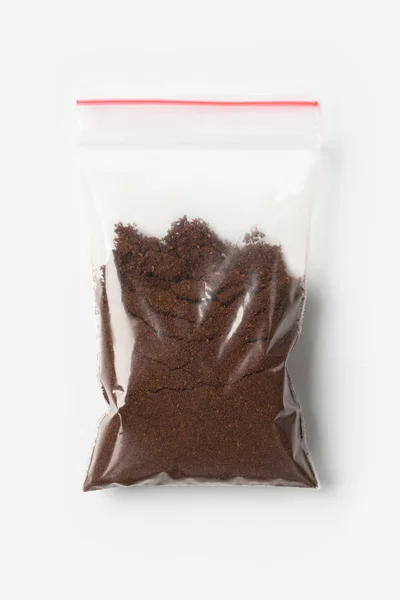 Plastic transparent zipper bag with half Brewed coffee powder isolated on white, Vacuum package mockup with red clip. Concept — Stock Photo, Image