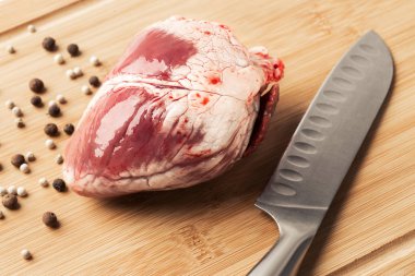 Ham koyun kalp kesim et için ahşap tahta bıçak ve baharatlar ile