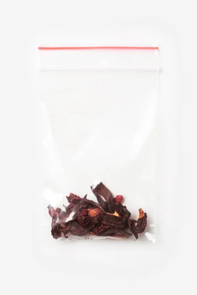 Sac à fermeture à glissière transparent en plastique avec un peu de thé en carcade isolé sur blanc, modèle d'emballage sous vide avec clip rouge. Concept . — Photo