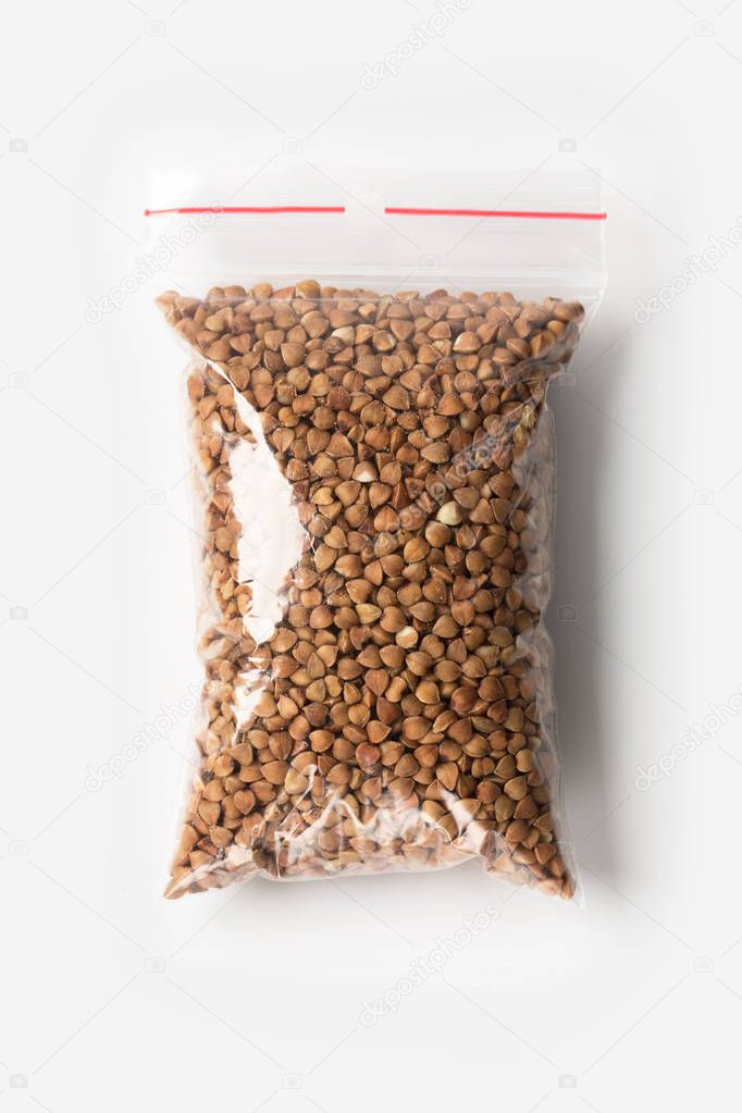 Plastic transparent zipper bag with full of premium buckwheat groats isolated on white, Vacuum package mockup with red clip. Concept