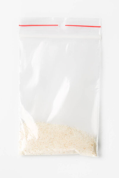 Пластиковый прозрачный пакет-молния с немного сухой сырой пшеницы semolinaisolated на белом, Вакуумный пакет макет с красным зажимом. Концепция
.