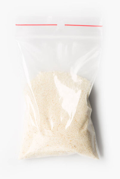 Пластиковый прозрачный пакет молнии с наполовину сухой сырой пшеничной манной, изолированный на белом, Вакуумный пакет макет с красным зажимом. Концепция
