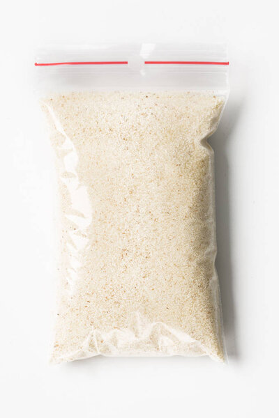 Пластиковые прозрачные молнии мешок с полным сухой сырой пшеничной манной изолированы на белом, Вакуумный пакет макет с красным зажимом. Концепция
