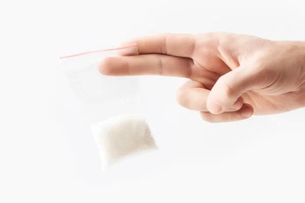 手拿着透明的塑料拉链袋半颗粒糖上白色、 真空包样机与红色剪辑孤立。概念. — 图库照片