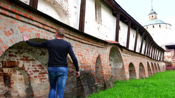 Tourist touches the historical reference massive brick walls of the monastery guarding against enemies — Stock Video