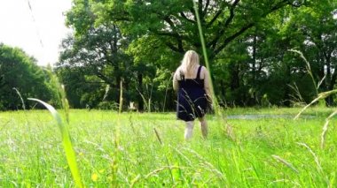 Yaz çayır yeşil çimenlerin üzerinde parkta yürürken elbiseli genç kız
