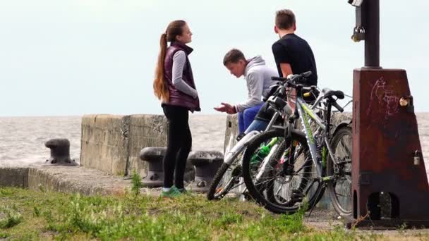Sportos fiatal, egészséges emberek ülnek a sziklák egy üres és hideg rakpart közelében a kikötői vas vontató — Stock videók