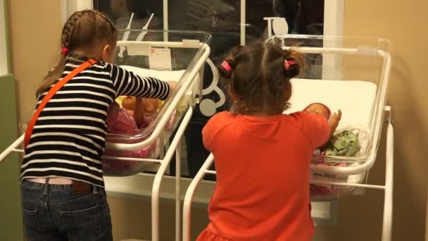 Kleine meisjes leren swaddle poppen in een wieg voor pasgeborenen — Stockvideo