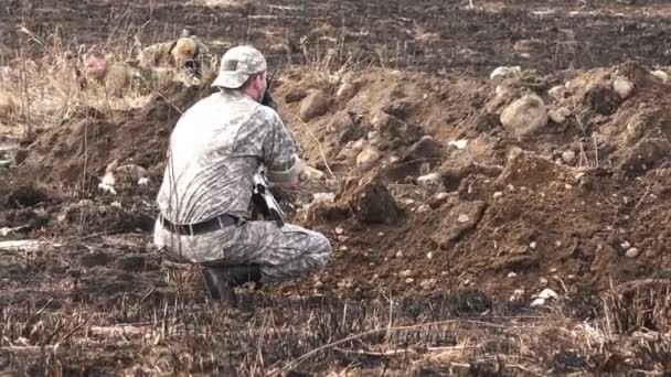 Soldado em camuflagem com uma arma das trincheiras é assistência militar através do rádio — Vídeo de Stock