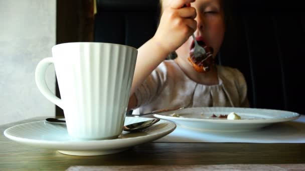 Meisje aan de tafel hebben een vork chocoladetaart — Stockvideo