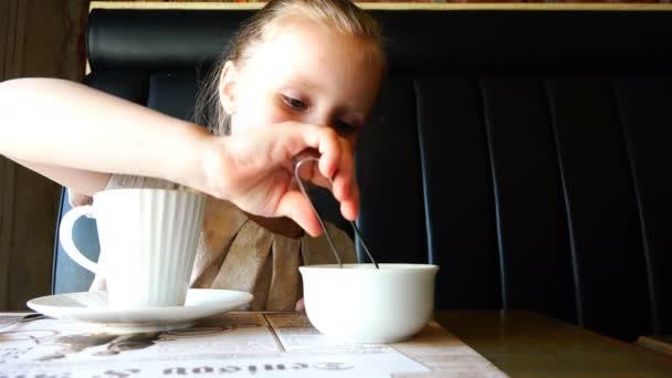 Девушка кладет кусочки сахара щипцы в чашку горячего напитка — стоковое видео