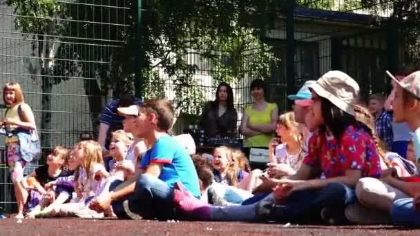 Barn i sommarkläder sitter på gummi täcka idrottsplats — Stockvideo