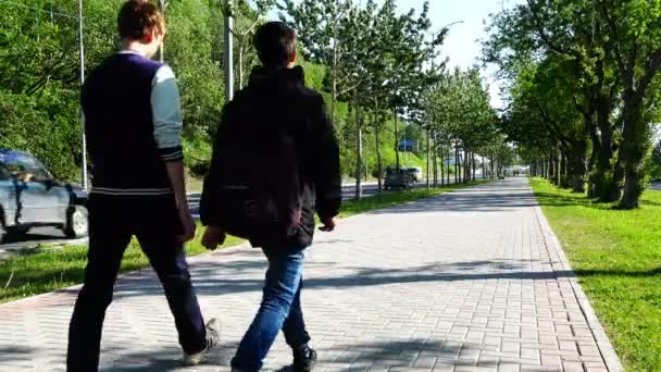 Dwóch nastolatek z plecakiem spaceru wzdłuż drogi w centrum handlowym — Wideo stockowe