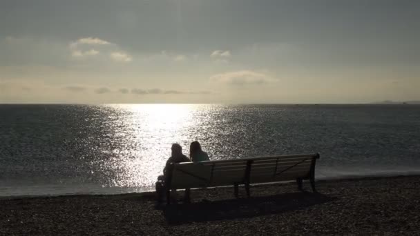 Niño y niña disfrutando de una vista del océano en la costa al atardecer — Vídeo de stock