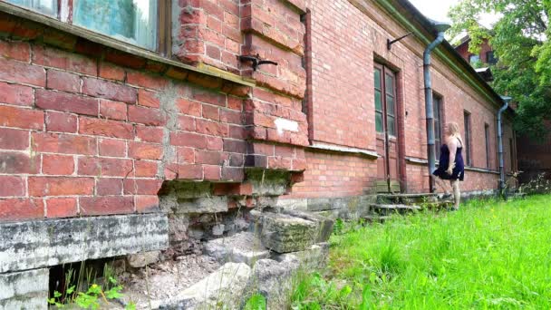 Een meisje onderzoekt een vervallen, historisch gebouw van een oude rode bakstenen gebouw — Stockvideo