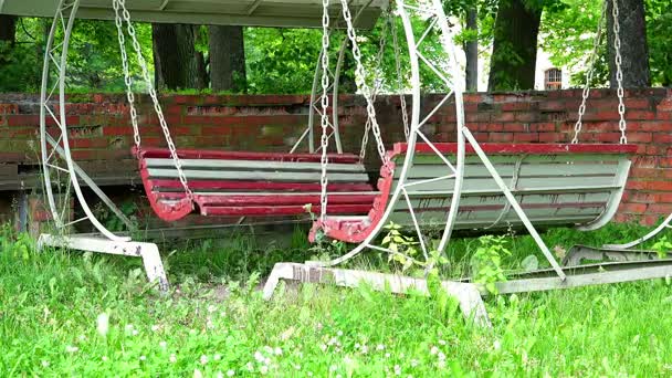 Balançoires en bois délabrées de forme circulaire dans une toile de fer sous un auvent couvert — Video