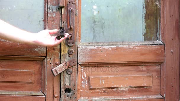 Una mano di persone controlla la serratura della porta chiusa tira la maniglia della porta di ferro di una vecchia porta di legno fatiscente — Video Stock