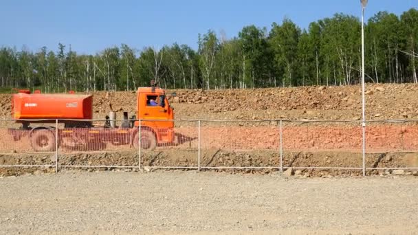 Freight transport with tanks follows a dirt road along the mesh fence — Stock Video