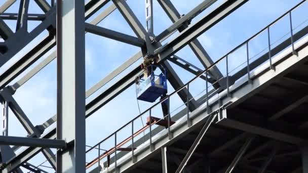 Сварщик в механическом подъемнике на платформе на высоте производит сварочные работы — стоковое видео