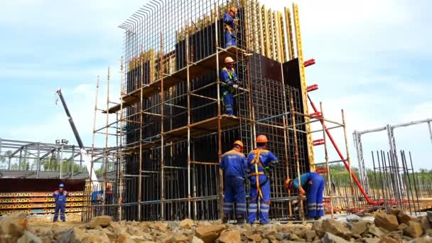Рабочие возводят армированную сетку под фундаментом на строительной площадке — стоковое видео
