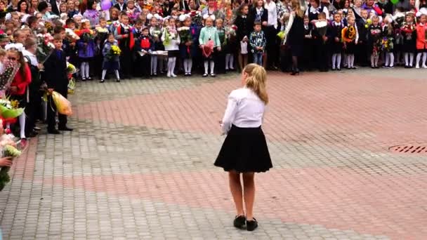 Een meisje in een witte blouse en zwarte rok dansen voor schoolkinderen — Stockvideo