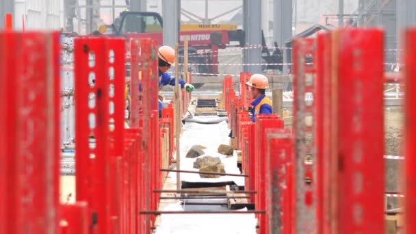 Los trabajadores detrás de las gradas rojas en la fundación en el sitio de construcción están trabajando en un cambio — Vídeo de stock