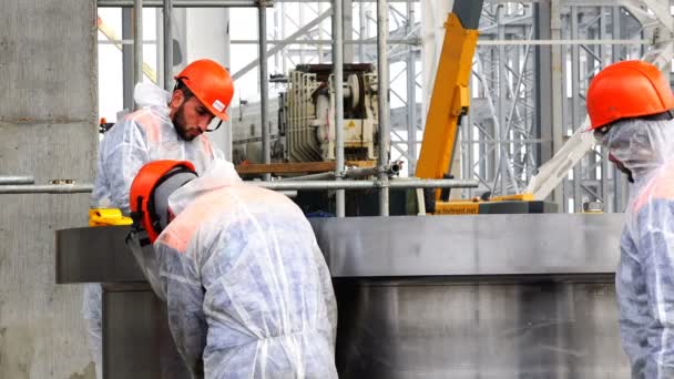 Group of hired labor in red helmets sharpen detail with special tools — Stock Video