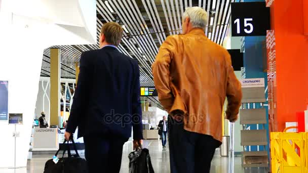 Aeropuerto Koltsovo dos hombres de negocios con equipaje de mano siguen la terminal del aeropuerto — Vídeos de Stock