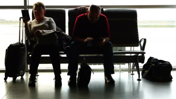 Passengers Busy Reading Books In Gadgets Are Sitting In The Airport Waiting Room
