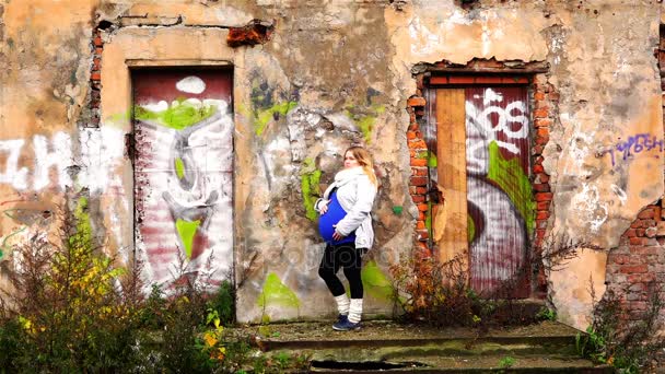 A menina grávida está de pé na rampa do alpendre de um edifício abandonado — Vídeo de Stock