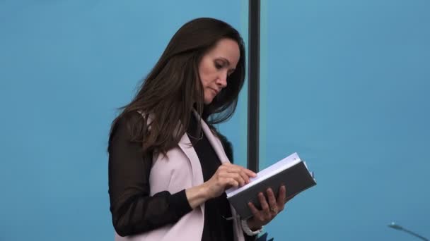 Une dame stricte et dominatrice lit un livre dans la rue — Video