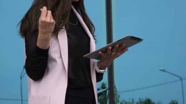 Een vrouw in strikte stijl leidt het bedrijf via een tablet — Stockvideo