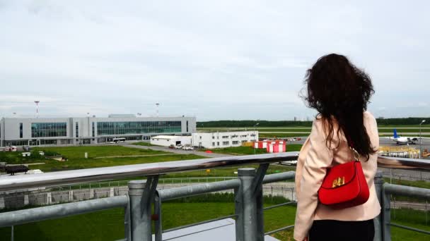 Девушка на платформе смотрит на летающий самолет, наблюдающий за ним. — стоковое видео