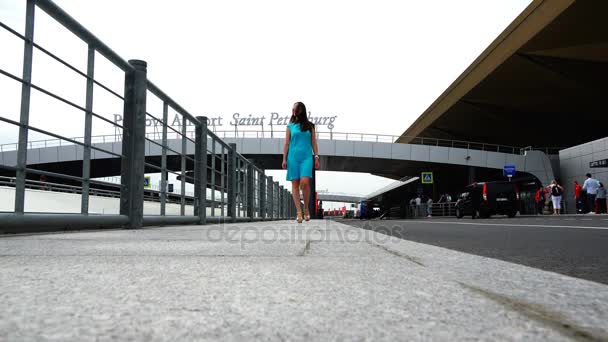 Uma menina em um vestido turquesa está andando ao longo da plataforma do aeroporto — Vídeo de Stock