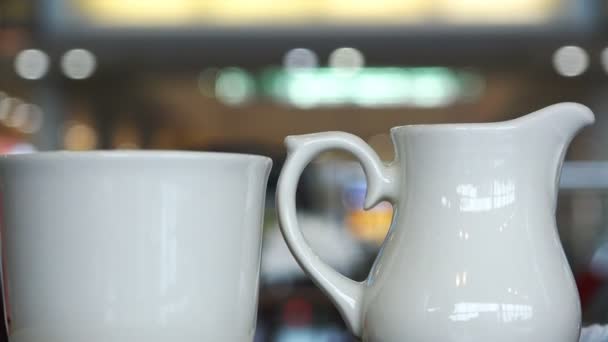 Чашка кофе и молочник на столе в бизнес-центре кафе — стоковое видео