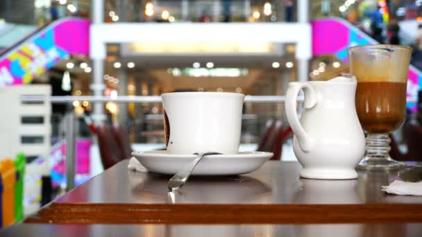 Main lève une tasse de café d'une soucoupe à une table dans un café — Video