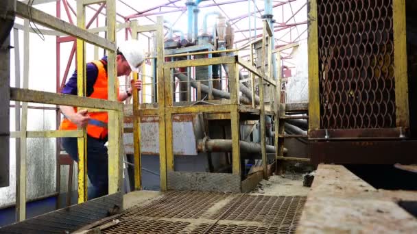 Trabajador en un casco y una forma especial sube las escaleras a la plataforma de trabajo — Vídeo de stock