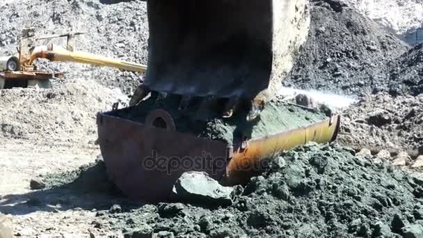 Ведро экскаватора распыляет большую часть грунта в железном контейнере. — стоковое видео