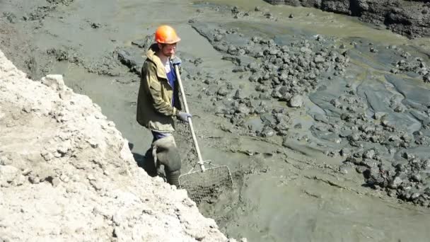 Un operaio in gomma con una marmotta estrae ambra in una trincea d'acqua . — Video Stock