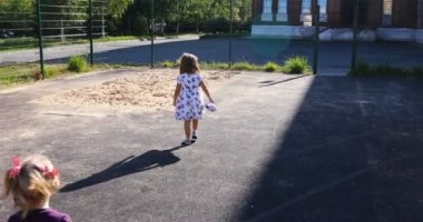 Kum havuzunda oturup renkli plastik oyuncaklarla oynayan iki şirin beyaz ve Latin bebeğin portresi. Küçük kızlar oyun alanında birlikte eğleniyorlar.