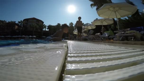 O menino saiu da água e subiu até a borda da piscina — Vídeo de Stock