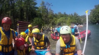 Kürekli turistler nehirde rafting yapmadan önce sandallarda otururlar.